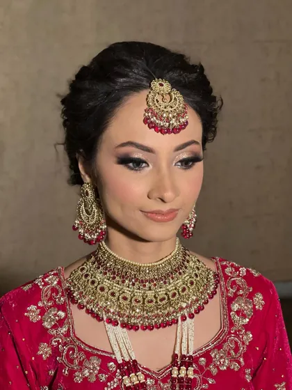 A soft, elegant pose showing the complete makeup and hair. The updo is perfect for keeping the hair neat and showcasing the heavy bridal jewelry.