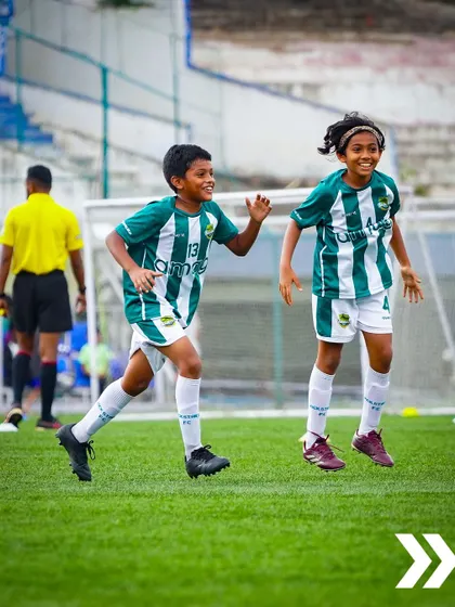 The joy and energy of youth football. Two young players celebrate a moment in the game with pure, uncontainable excitement.