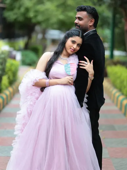 A tender moment from a baby shower shoot. The mom-to-be is glowing in a light pink tulle gown with delicate ruffle details on the shoulders and hem.