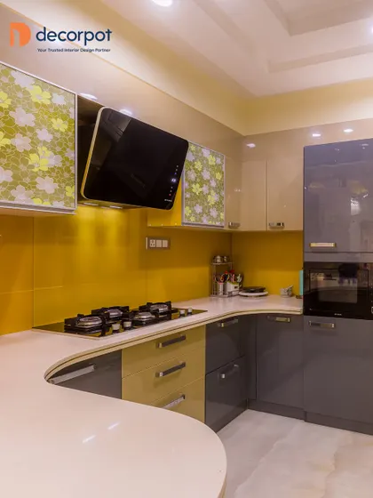 A unique and artistic kitchen design featuring a curved countertop. The combination of sunny yellow, grey, and floral-patterned cabinets creates a playful and eclectic vibe that is full of personality.