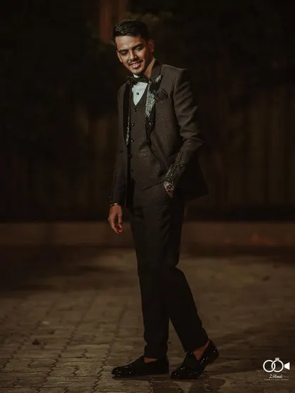A dapper full-length portrait of the groom in his classic black tuxedo, looking sharp for the reception.