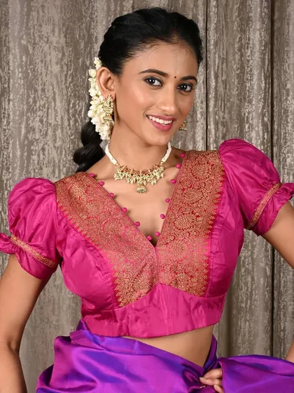 A beautiful pearl and kundan-style choker worn by a model. The necklace sits high on the neck, perfectly complementing the V-neck of her vibrant pink blouse.