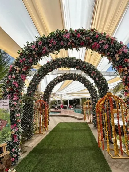 A beautiful floral archway tunnel for a daytime event. The series of arches covered in pink and green flowers creates a stunning photo opportunity and a memorable entrance.