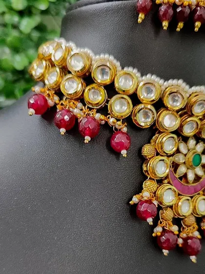 A detailed view of a rental choker with kundan work and red bead drops. This is a classic design that pairs well with many bridal outfits.