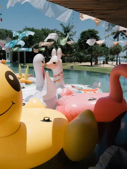 Fun and quirky pool floats, including a giant flamingo and duck, ready for a tropical-themed pool party at a resort in Bali.