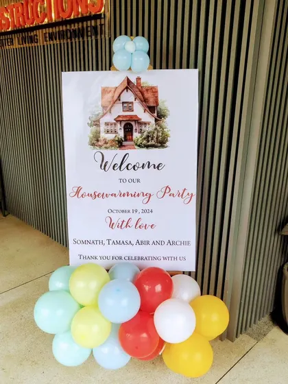 A personalized welcome sign on an easel for a housewarming party, complete with a small balloon cluster to greet guests.