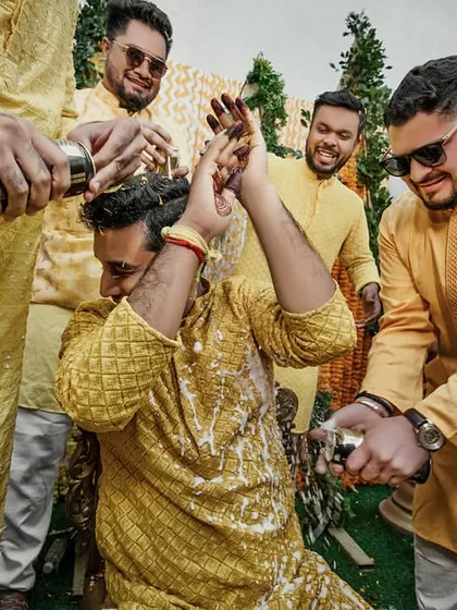 The groom tries to shield himself, but there's no escaping the fun of the Haldi ceremony. A great candid moment with his groomsmen.