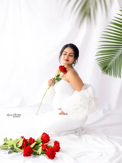 A kneeling pose in the white gown, surrounded by red roses, creating a beautiful contrast of colors.