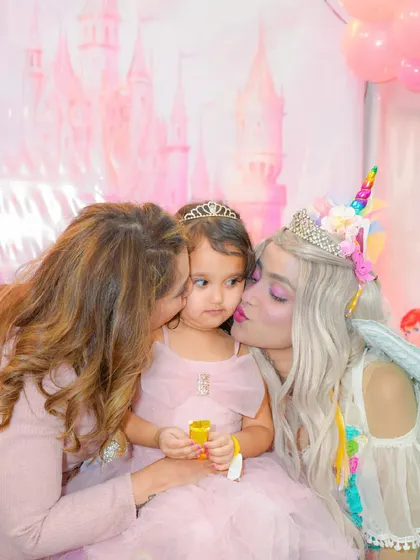 A magical moment as the birthday girl gets a kiss from her mom and a unicorn princess character.