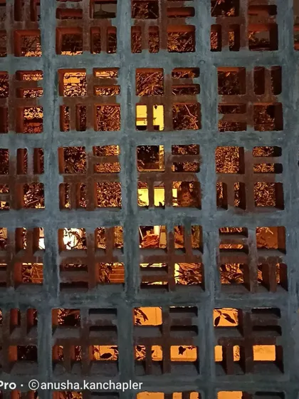 A close-up of the custom-designed breeze block jali wall during construction. The warm interior light filtering through the pattern shows how this feature works to create visual interest and texture.