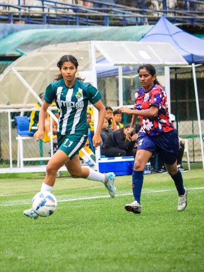 An attacker sprints with the ball down the wing, looking to create a scoring opportunity for her team.