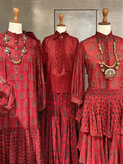 A collection of beautiful red block-printed dresses and tops, styled with chunky tribal necklaces for a bohemian-chic vibe.