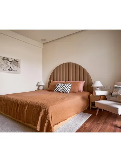 In this bedroom, we designed a custom arched, channel tufted headboard and a minimalist wooden armchair. The space is a fusion of rustic and elegant styles, using honest materials to create a peaceful haven.