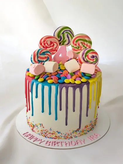 A fun candy drip cake for a 4th birthday. The colorful drips, sprinkles, and lollipops make it a joyful and delicious treat.
