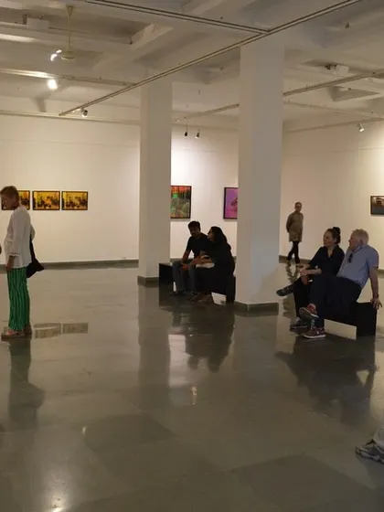 A view of the gallery space with visitors seated and observing the art.