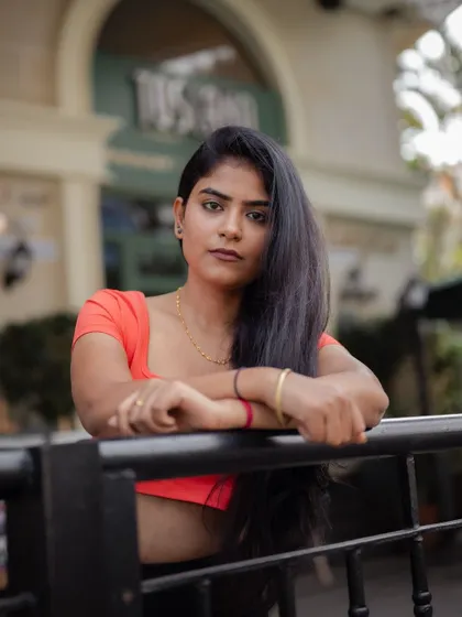 A close-up portrait of a model leaning against a railing. The focus is on her expression and the urban atmosphere of the shot.
