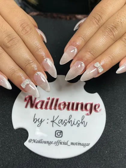 A beautiful 9D cat-eye effect on stiletto nails, giving a pearlescent, multi-dimensional look, finished with delicate rhinestone bows.