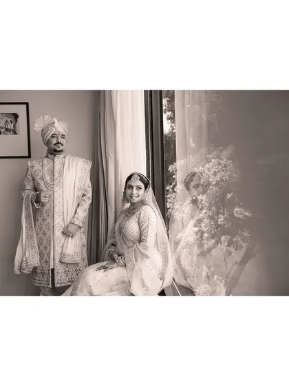 A classic black and white portrait of the couple, their reflection in the window adding a layer of depth and artistry.