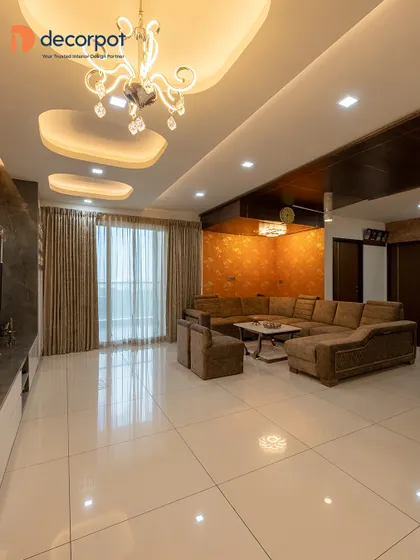 This expansive living room features a large U-shaped sofa, perfect for entertaining. The combination of a textured accent wall and a modern chandelier adds a touch of drama and luxury to the space.