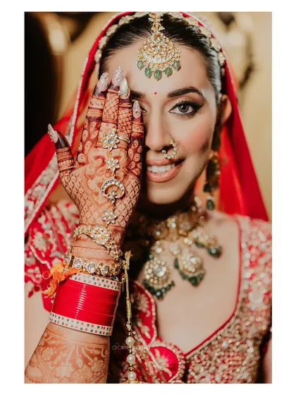 A classic bridal pose, with the bride showing off her intricate henna design.