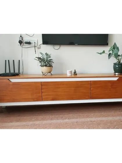 A mid-century modern inspired TV console crafted from solid wood with a contrasting white frame. The clean lines and angled legs give it a sleek, timeless appeal, while providing ample storage for media essentials.