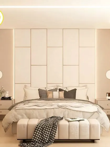 A minimalist and elegant bedroom with a large, panelled headboard and simple circular wall sconces.