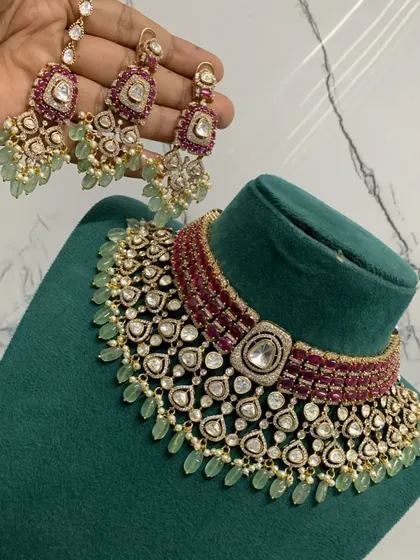 An exceptionally crafted bridal necklace set combining ruby-colored stones with mint-green bead drops. This piece demonstrates our ability to create complex, multi-colored designs with premium Moissanite stones for a rich, designer appeal.