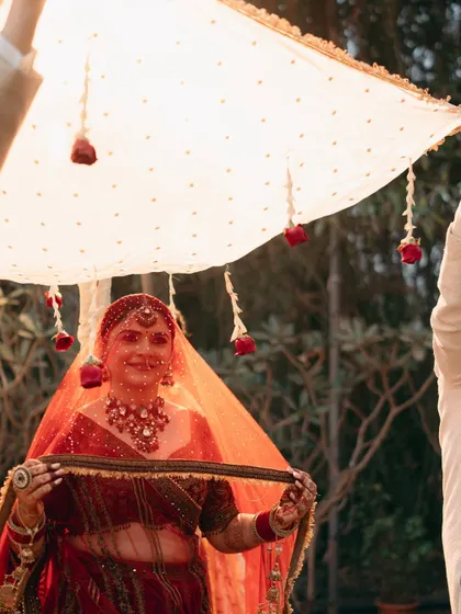 The bride holds the varmala, ready for the ceremony. The simple phoolon ki chaadar with hanging roses adds a delicate and traditional touch.