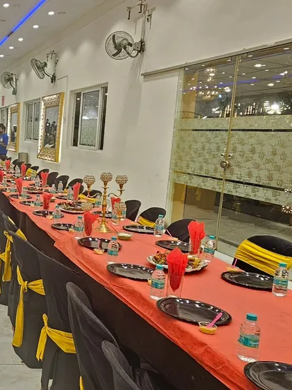 An elegant groom's table setup with black and gold themed decor. The black plates and chair covers with yellow sashes create a sophisticated look.
