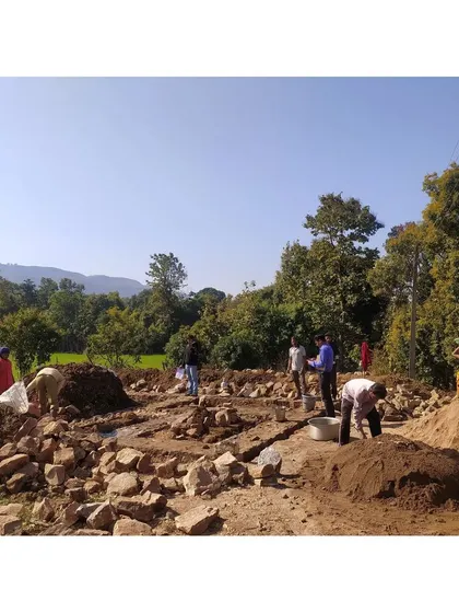 A wide shot of the construction site for a homestay, with community members working together. This image captures the scale of the collaborative effort involved in our community-based projects.