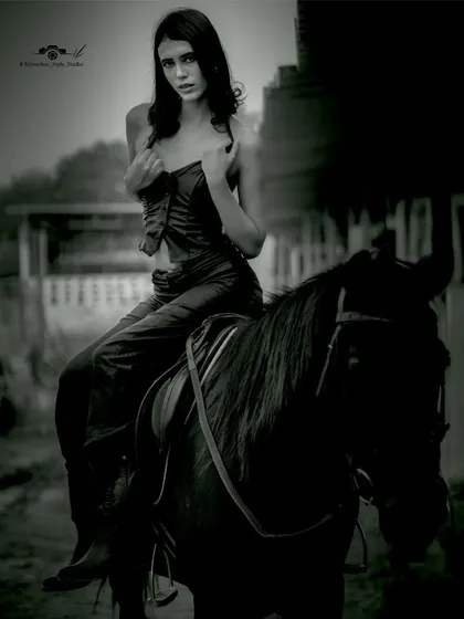 A dramatic, moody black and white shot of a model on horseback, showcasing a more artistic and edgy style of photography.