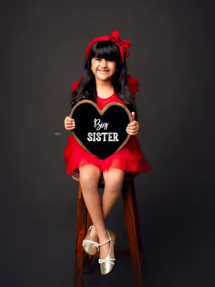And here we have a proud Big Sister. She is absolutely adorable in her red dress, holding the announcement sign.
