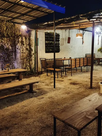 The combination of a vertical garden, climbing plants, and simple wooden benches gives this cafe a rustic, garden-to-table feel.