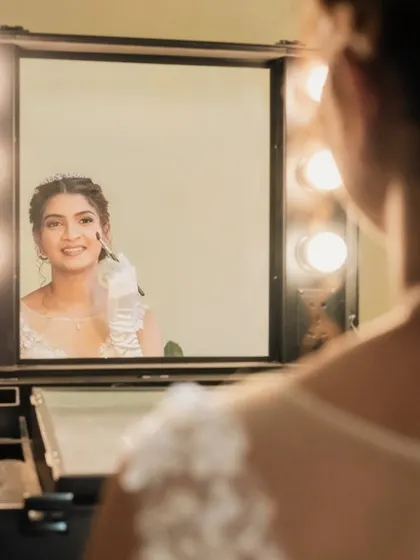 A look in the mirror. This creative shot captures the bride touching up her makeup, looking absolutely radiant.