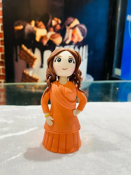A detailed look at the handcrafted fondant figurine, showcasing the careful work on her dress and curly hair.