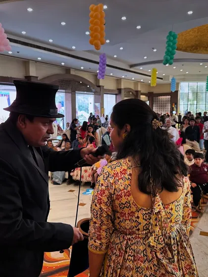 Engaging with an audience member during a stage show at a large wedding event. Interactive magic is the best way to make guests feel like they are part of the spectacle.