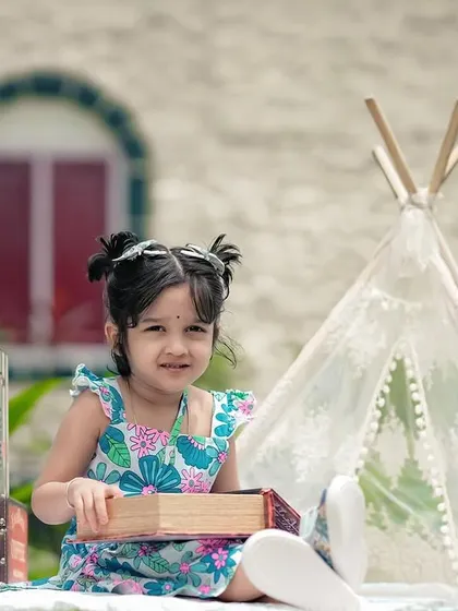 This little explorer is ready for her next adventure with a globe and vintage suitcases in our outdoor camping setup.