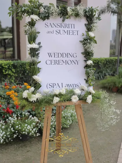 A simple and elegant welcome easel, framed with fresh white flowers and greenery, directing guests to the spa lawns.