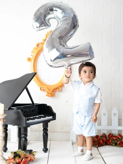 Celebrating two! This toddler holds a large number "2" balloon during his second birthday photoshoot, marking another major milestone in style.