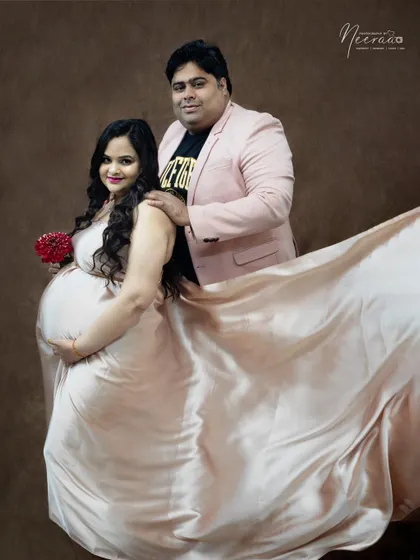 The satin gown catches the light beautifully, creating a soft and glamorous feel. The fabric flows around the couple, adding a touch of drama to this romantic studio portrait.