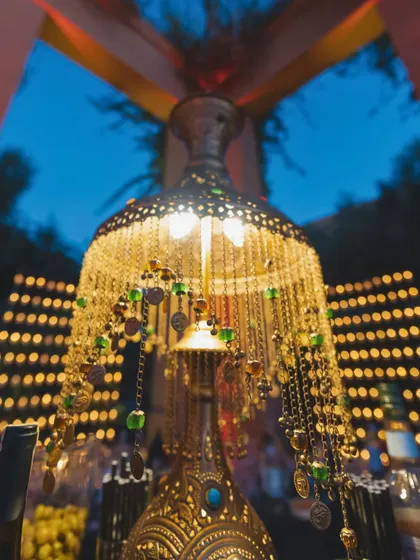 A close-up of an ornate Moroccan table lamp, with intricate metalwork and colorful bead details.