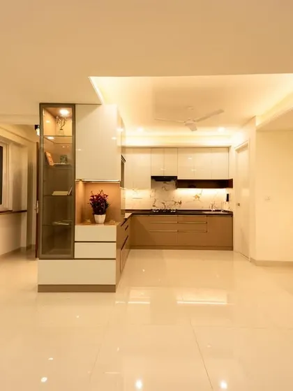 This view shows the connection between the living area and the kitchen. The consistent color palette of whites and earthy tones, along with recessed ceiling lights, creates a unified and spacious environment.