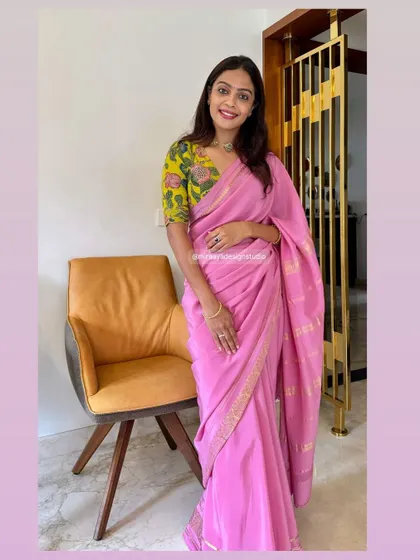 A full-length view of Bhavani's outfit. The vibrant yellow floral blouse adds a cheerful and modern twist to her classic pink saree.