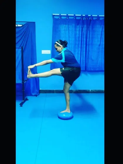 A standing hamstring stretch performed on a balance disc. This drill is part of our flexibility training, designed to increase range of motion for powerful strokes.