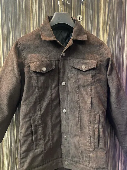 This is a custom-made corduroy jacket in a rich brown, featuring a classic trucker design with flap pockets and a warm, quilted inner lining for extra comfort.