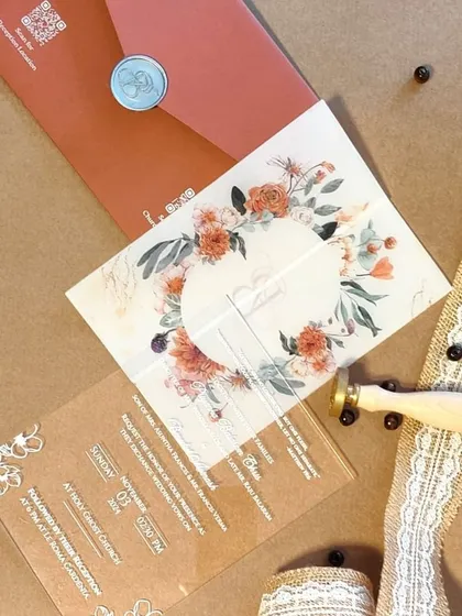 A full view of the coral-themed acrylic invitation suite, showing the vellum wrap, wax seal, and the beautiful floral design.