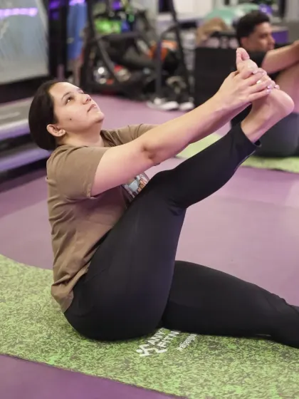 Find your focus and build strength in our group yoga sessions. This image captures a member deep in a stretch, showcasing the calm and determination that our yoga classes help cultivate on the mat.