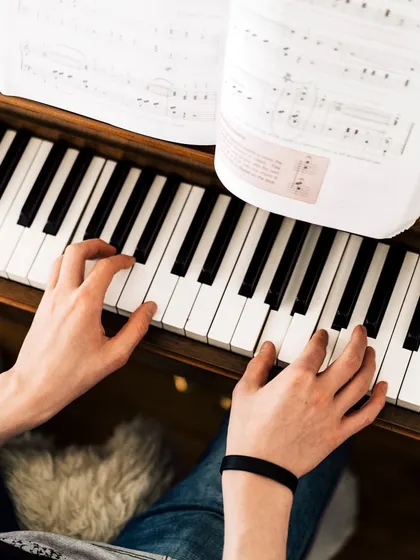 An overhead view of a student's hands on the piano keys, deeply engaged with the sheet music. This captures the focus and dedication we instill in our students as they learn to play.
