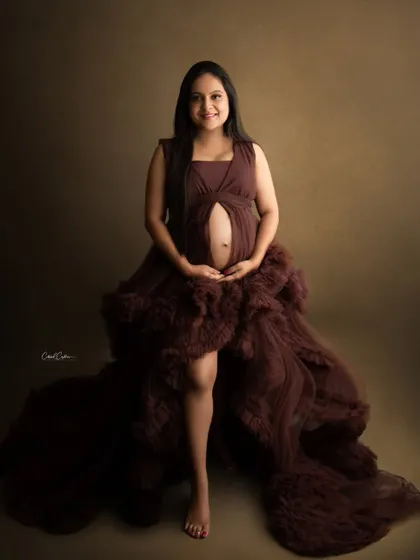 A happy and confident portrait of a mom-to-be in a beautiful, multi-layered brown gown.