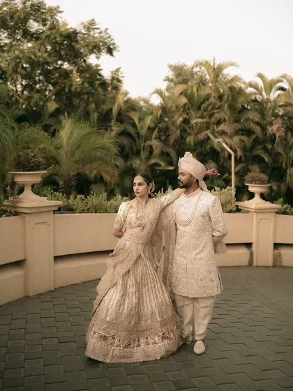 A full-length portrait of the couple, showcasing the grandeur of their coordinated wedding outfits.